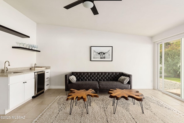 living room with ceiling fan, wet bar, light tile patterned floors, and beverage cooler