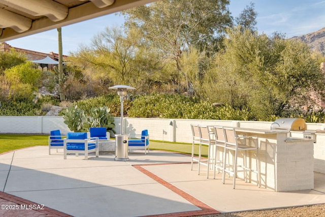 view of patio with fence, area for grilling, outdoor dry bar, a mountain view, and grilling area