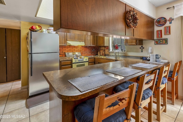 575 N Robles Rd, Oracle, AZ 85623 - kitchen with freestanding refrigerator, gas stove, under cabinet range hood, a sink, and a peninsula