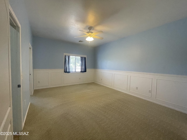 9454 E Lanterra Ct, Tucson, AZ 85710 - spare room with light carpet, wainscoting, ceiling fan, and a decorative wall