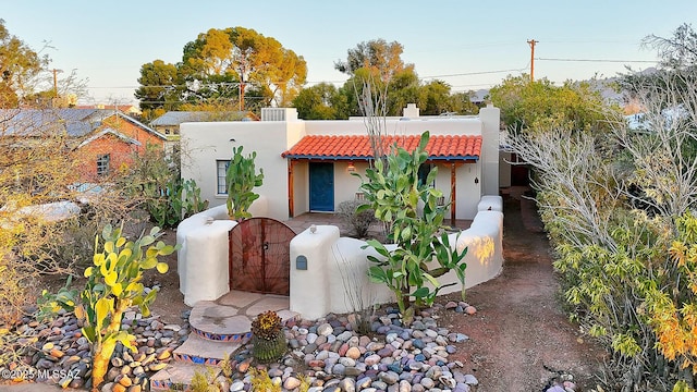 view of front of house featuring stucco siding, a tile roof, fence private yard, and a gate