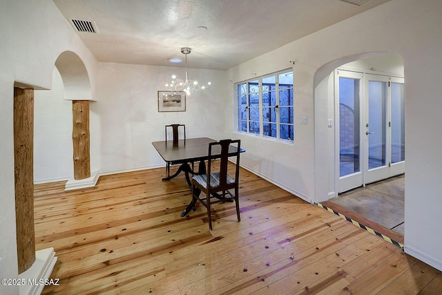 dining area with visible vents, arched walkways, and hardwood / wood-style flooring