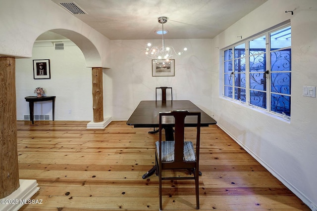 unfurnished dining area with wood-type flooring, visible vents, and arched walkways