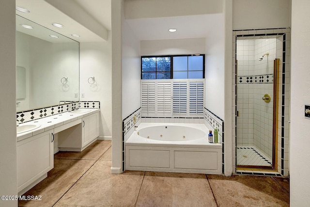full bath featuring a sink, a tub with jets, a stall shower, tile patterned flooring, and double vanity