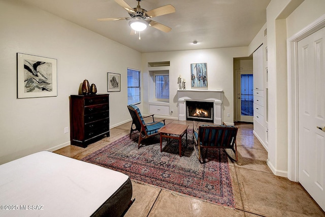 bedroom with ceiling fan, baseboards, and a fireplace with flush hearth