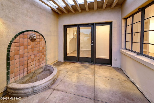 entrance to property with stucco siding and a patio