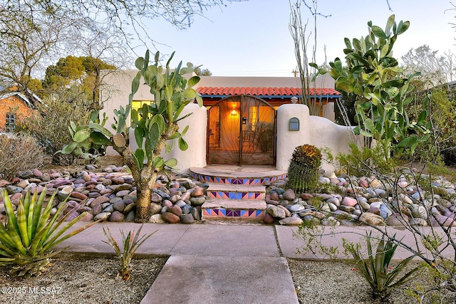 view of front of house featuring stucco siding, a tile roof, and fence