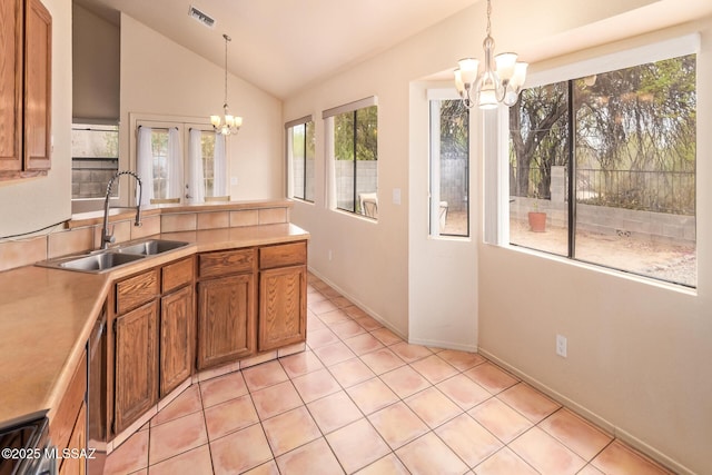 4755 W Lessing Ln, Tucson, AZ 85742 - kitchen featuring a chandelier, a sink, brown cabinets, vaulted ceiling, and hanging light fixtures