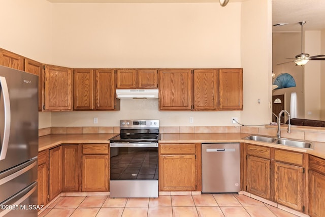 4755 W Lessing Ln, Tucson, AZ 85742 - kitchen with appliances with stainless steel finishes, a sink, under cabinet range hood, brown cabinets, and a ceiling fan