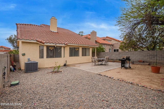 4755 W Lessing Ln, Tucson, AZ 85742 - rear view of house featuring central AC unit, a tiled roof, a chimney, a fenced backyard, and stucco siding