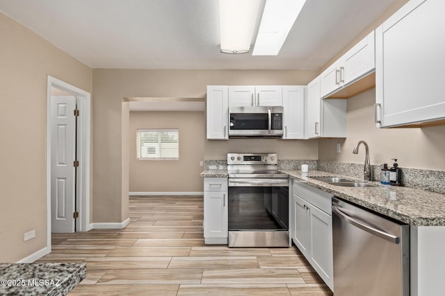 1239 N Beverly Ave, Tucson, AZ 85712 - kitchen featuring appliances with stainless steel finishes, a sink, light wood finished floors, light stone countertops, and white cabinetry