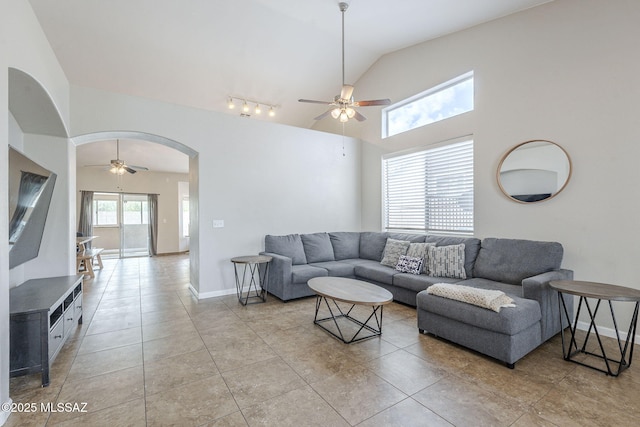 living room with ceiling fan, light tile patterned flooring, lofted ceiling, and arched walkways