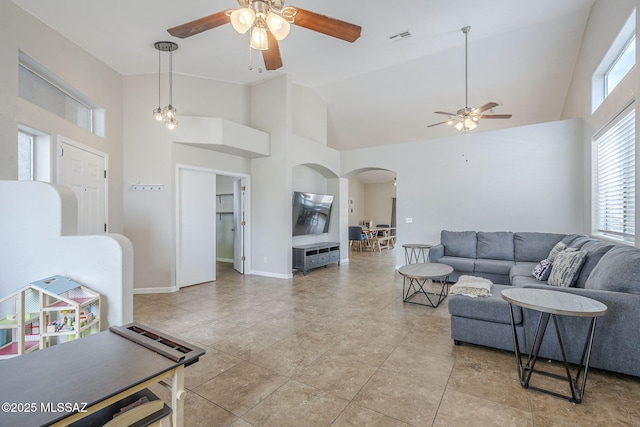 living area with high vaulted ceiling, a healthy amount of sunlight, visible vents, ceiling fan, and arched walkways