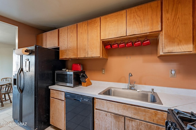kitchen featuring a sink, light tile patterned flooring, light countertops, and black appliances
