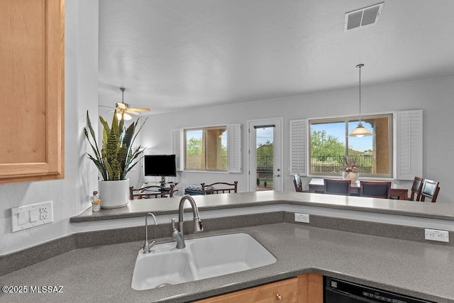kitchen with a sink, a ceiling fan, dishwasher, hanging light fixtures, and dark countertops