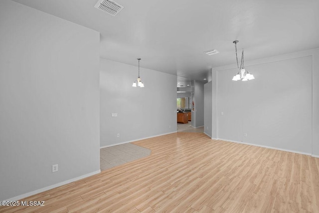 unfurnished living room featuring wood finished floors, a chandelier, and baseboards