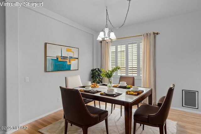 dining space with a chandelier, light wood finished floors, and baseboards