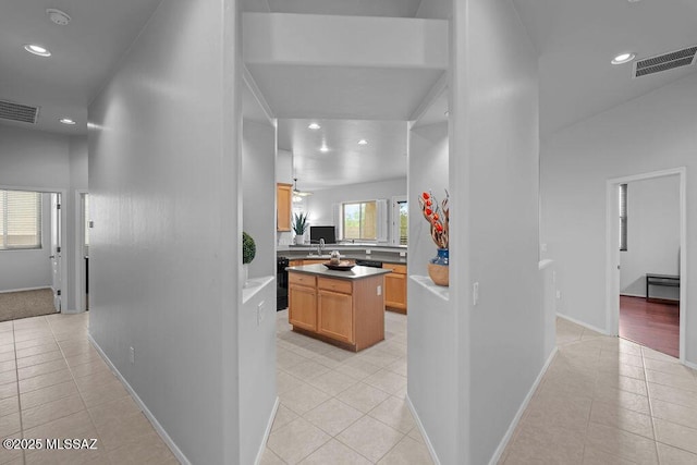 hallway featuring light tile patterned flooring, recessed lighting, a sink, and baseboards