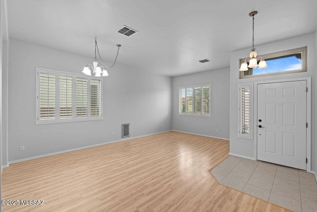 foyer entrance with a chandelier, light wood-type flooring, and baseboards