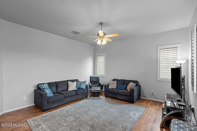 living room featuring wood finished floors, a ceiling fan, and baseboards