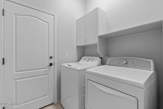 clothes washing area with cabinet space and washer and clothes dryer