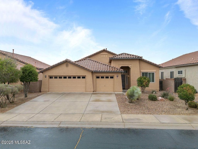 mediterranean / spanish house featuring stucco siding, an attached garage, a tile roof, and concrete driveway