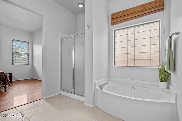 bathroom featuring a garden tub, a stall shower, tile patterned floors, and baseboards