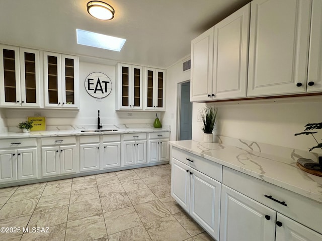 2838 E Beverly Dr, Tucson, AZ 85716 - kitchen featuring a sink, a skylight, and white cabinets