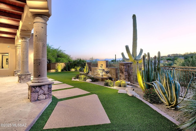 6015 N Camino Preciado, Tucson, AZ 85718 - yard at dusk featuring a fenced backyard, a patio area, and a fireplace