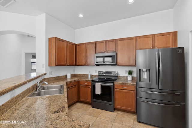 385 E Cedarvale Rd, Tucson, AZ 85704 - kitchen featuring stainless steel appliances, brown cabinetry, light tile patterned floors, arched walkways, and recessed lighting