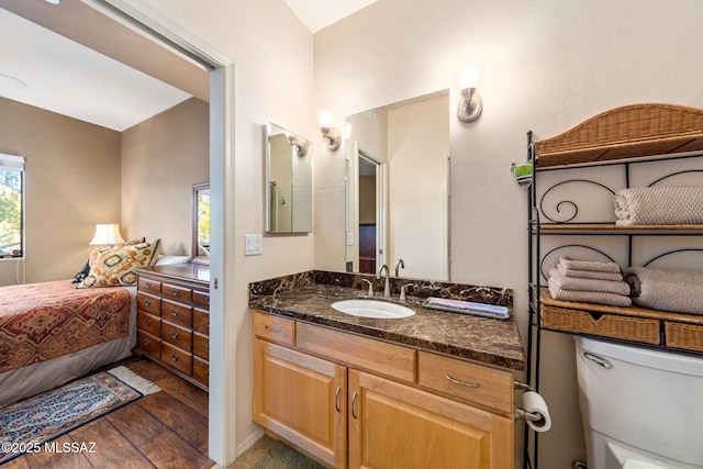 ensuite bathroom with wood finished floors, toilet, and vanity