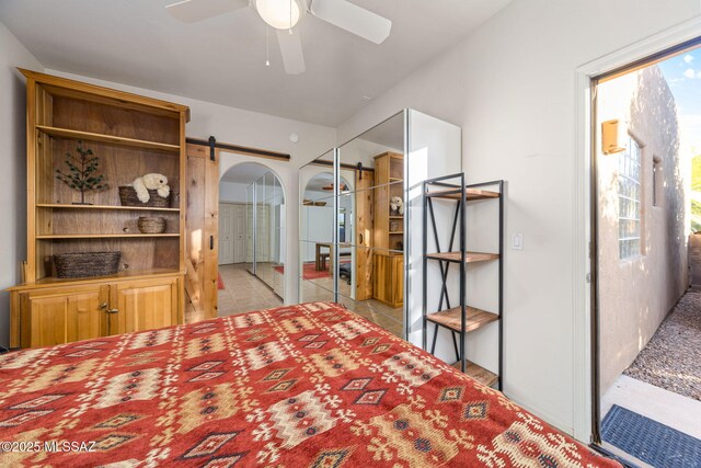 bedroom with a barn door, arched walkways, and ceiling fan