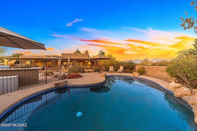 pool at dusk featuring a patio area and fence