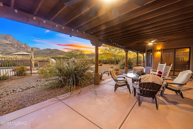view of patio featuring a mountain view, fence, outdoor dining area, and a ceiling fan