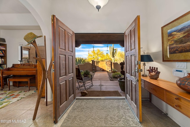 doorway with arched walkways, light tile patterned floors, and french doors