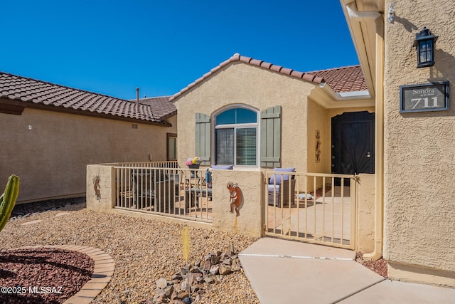 711 W Camino Del Rosal, Sahuarita, AZ 85629 - view of exterior entry featuring stucco siding, a tile roof, fence, and a gate
