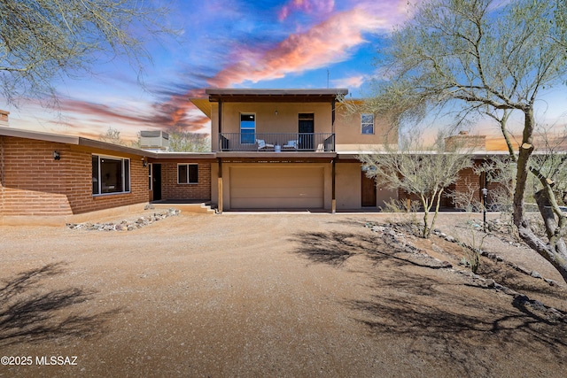 6891 N Camino Verde, Tucson, AZ 85743 - view of front of home featuring an attached garage, dirt driveway, stucco siding, and a balcony