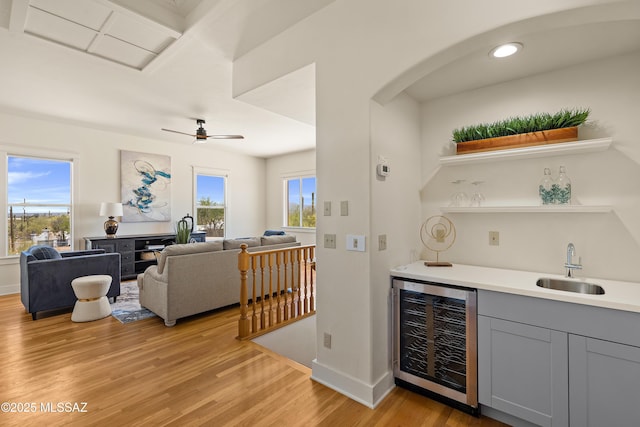 6891 N Camino Verde, Tucson, AZ 85743 - bar with wine cooler, baseboards, a sink, wet bar, and light wood-type flooring