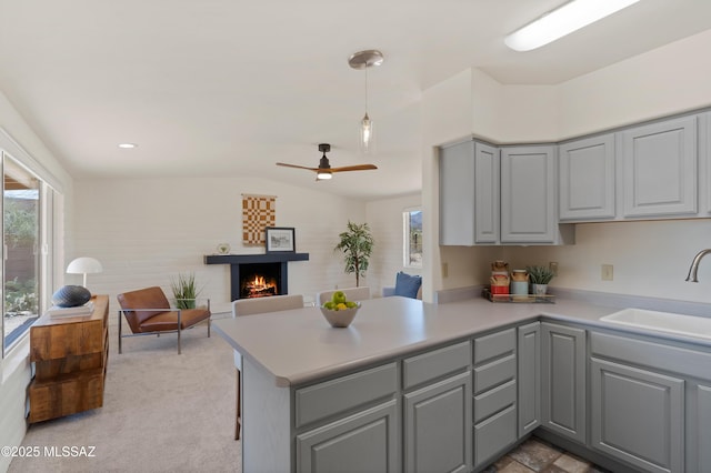 6891 N Camino Verde, Tucson, AZ 85743 - kitchen featuring lofted ceiling, gray cabinetry, a sink, open floor plan, and a lit fireplace