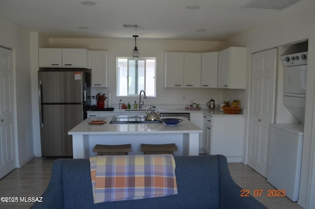 1700 E Water St, Tucson, AZ 85719 - kitchen featuring freestanding refrigerator, stacked washer / drying machine, a sink, and white cabinetry