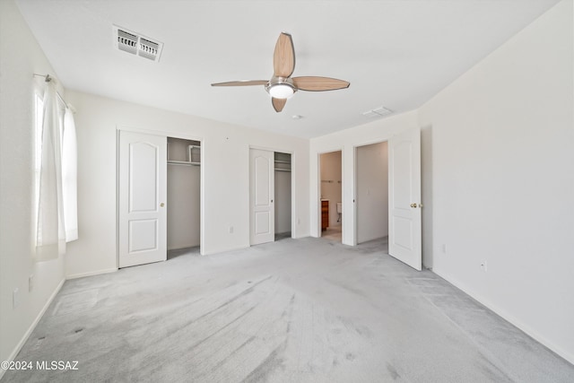 9410 E Grapevine Spring Pl, Tucson, AZ 85710 - unfurnished bedroom featuring light colored carpet, multiple closets, visible vents, a ceiling fan, and baseboards