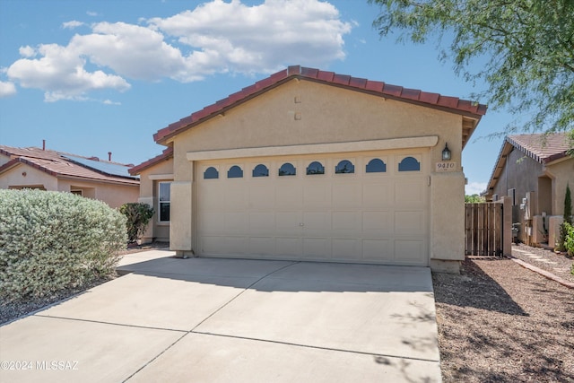 9410 E Grapevine Spring Pl, Tucson, AZ 85710 - mediterranean / spanish-style home featuring an attached garage, stucco siding, a tiled roof, and driveway