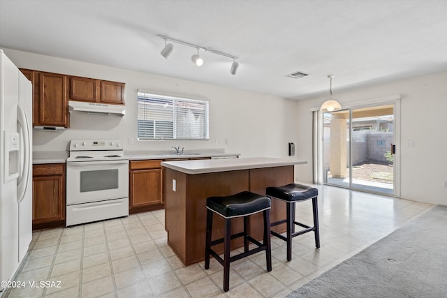 9410 E Grapevine Spring Pl, Tucson, AZ 85710 - kitchen featuring brown cabinetry, white appliances, visible vents, under cabinet range hood, and light countertops