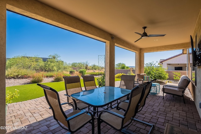 view of patio with outdoor dining space, ceiling fan, and fence