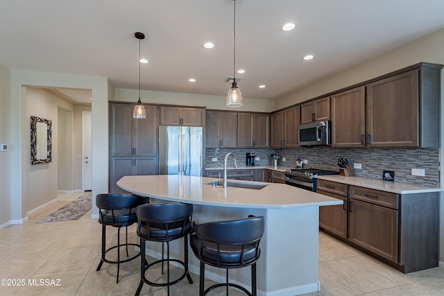 kitchen featuring stainless steel appliances, a sink, tasteful backsplash, a kitchen bar, and light countertops