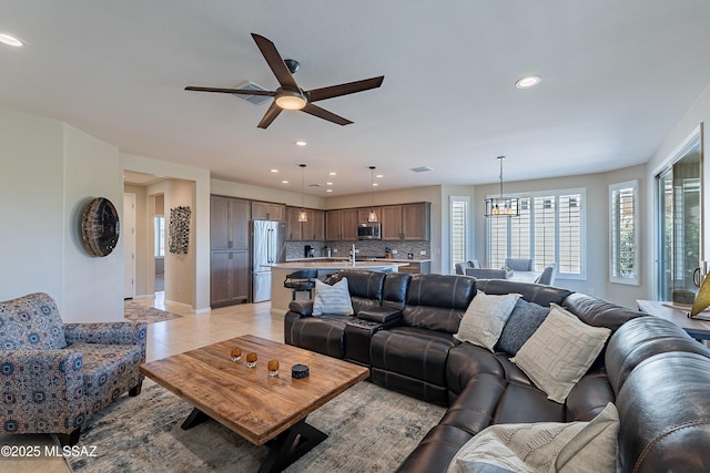 living room featuring recessed lighting, plenty of natural light, a ceiling fan, baseboards, and a chandelier