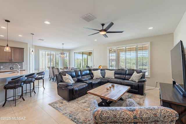 living area featuring recessed lighting, ceiling fan, light tile patterned floors, baseboards, and a chandelier