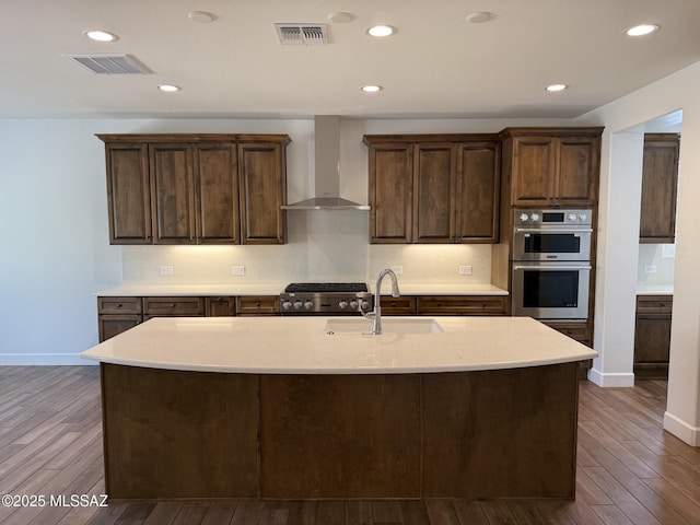 61662 E Quartzite Rd, Oracle, AZ 85623 - kitchen featuring wall chimney exhaust hood, a sink, double oven, dark wood-style floors, and light stone counters