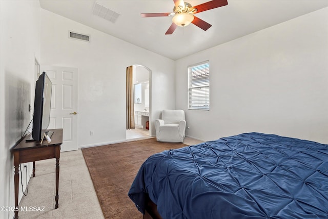 5523 W Carriage Dr, Tucson, AZ 85742 - bedroom with arched walkways, light carpet, lofted ceiling, baseboards, and connected bathroom