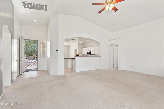5523 W Carriage Dr, Tucson, AZ 85742 - unfurnished living room with light carpet, high vaulted ceiling, ceiling fan, arched walkways, and baseboards